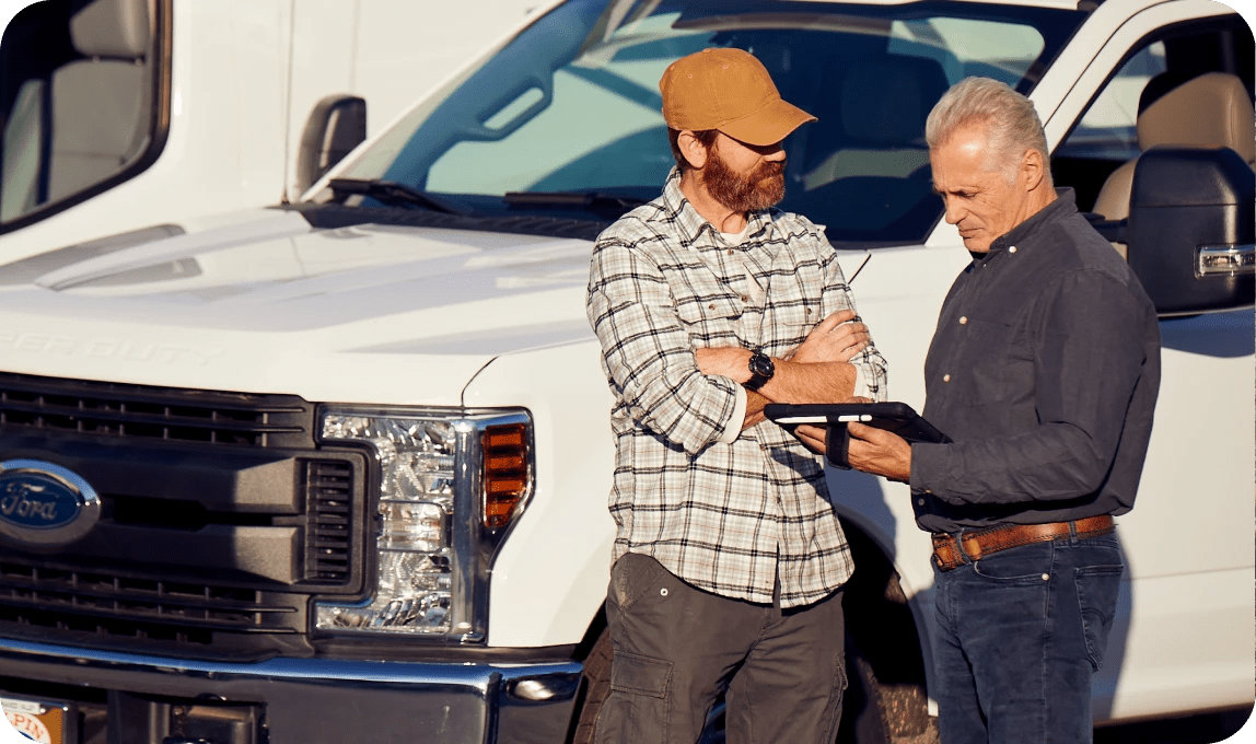 contractor and foreman on construction job site reviewing information on a tablet