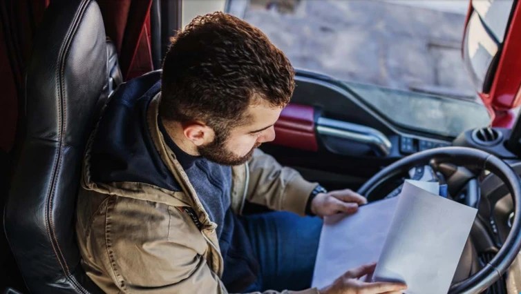 man in semi truck reading paperwork