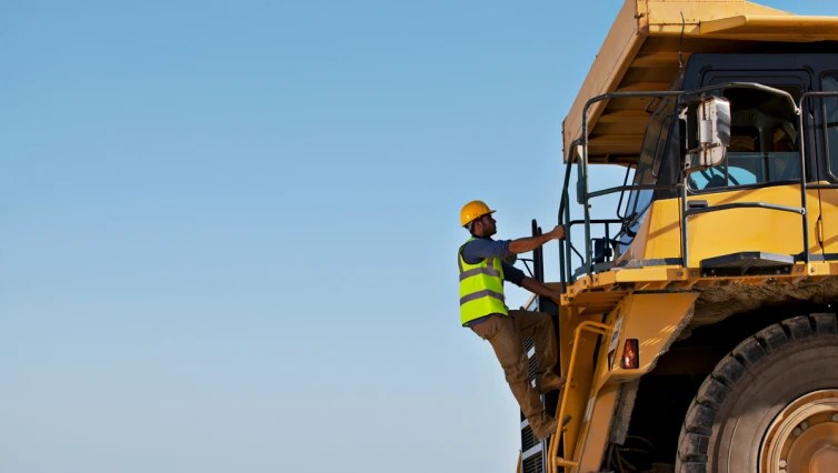 construction worker on front of large construction vehicle